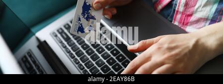 Woman holds credit card and types on laptop keyboard Stock Photo