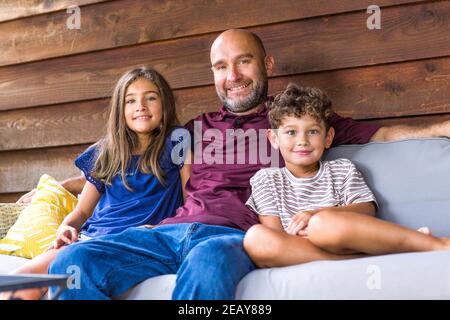 Hispanic father sitting and hugging his children. Stock Photo