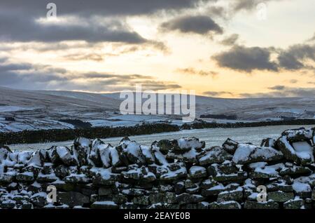 A snow covered dry stone wall against a late afternoon sky in Weardale, County Durham, North Pennines AONB Stock Photo