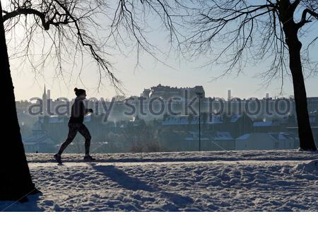 Edinburgh, Scotland, UK. 11th Feb 2021. People enjoying jogging through the park on a Glorious sunny but freezing morning in a snow covered Inverleith park. View of Edinburgh Castle.  Credit: Craig Brown/Alamy Live News Stock Photo