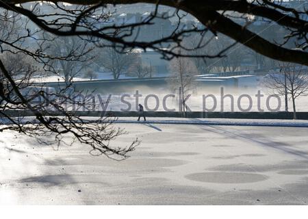Edinburgh, Scotland, UK. 11th Feb 2021. People enjoying a Glorious sunny but freezing morning in a snow covered Inverleith park. View over a frozen Inverleith pond with freezing ground mist. Credit: Craig Brown/Alamy Live News Stock Photo