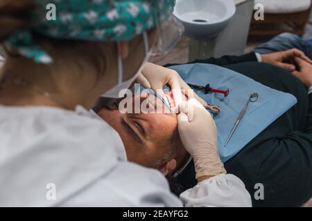 Female dentist with a patient in her office. Patient with open mouth and woman dentist working. dental health concept.