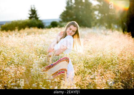 girl in a field in the setting sun with daisies Stock Photo