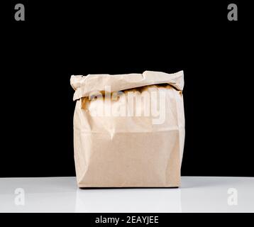 The empty open brown paper bag on black background. Stock Photo