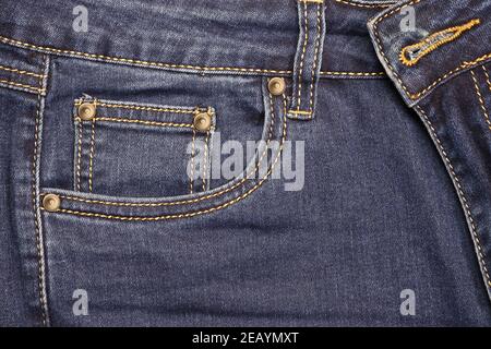 Thread-stitched front pocket of blue fashion jeans with studs. Stock Photo