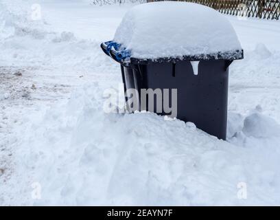 Garbage can completely snowed in in the snow chaos Stock Photo