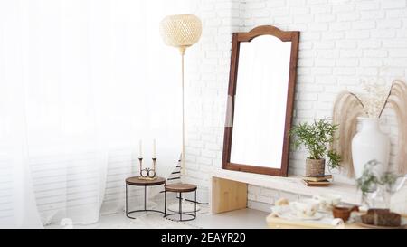 Modern bedroom with white walls, mirror in rustic, boho and scandinavian style. Eco friendly interior Stock Photo