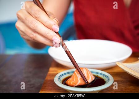 Salmon sashimi with soy sauce been picked up with chopsticks Stock Photo