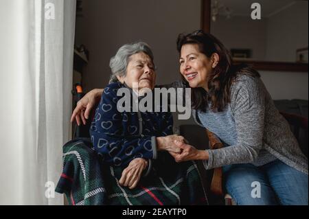 Old sick woman in wheelchair next to smiling daughter. Third age, Home care concept. Stock Photo