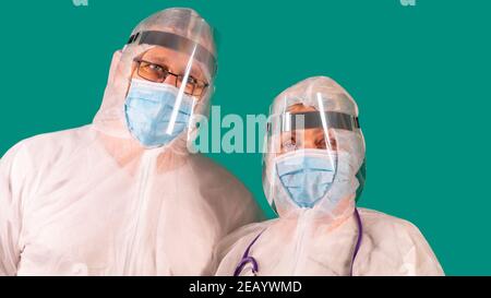 Two doctors with face shields in PPE suit uniforms wearing medical protective Masks Stock Photo