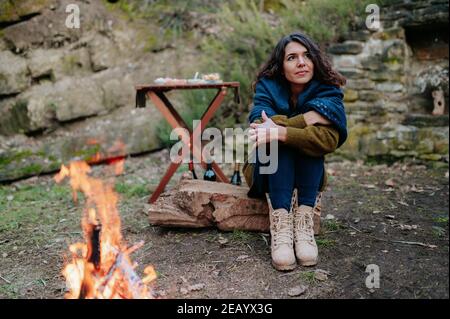 Young woman sitting next to a fire during a winter picnic. Stock Photo