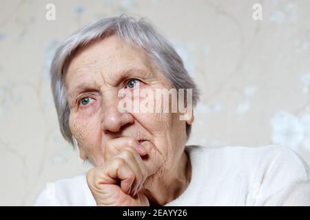 Elderly woman with peaceful expression thought about something. Female with gray hair and wrinkled skin, concept of memories, old age Stock Photo