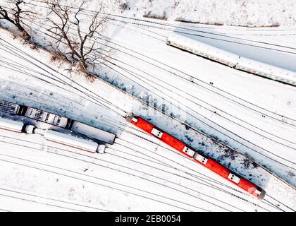 Top view of cargo trains and passanger diesel multiple unit - DMU. Aerial top view from flying drone of snow covered freight trains on the railway tra Stock Photo