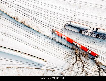 Top view of cargo trains and passanger diesel multiple unit - DMU. Aerial top view from flying drone of snow covered freight trains on the railway tra Stock Photo