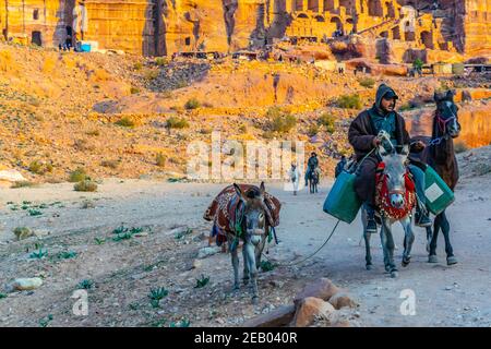 PETRA, JORDAN, JANUARY 2, 2019: bedouin riding a donkey in front of the urn tomb in petra, Jordan Stock Photo