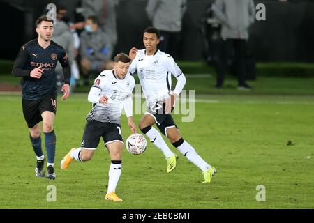 Swansea, UK. 10th Feb, 2021. Paul Arriola of Swansea city (c) and Morgan Whittaker of Swansea city (r) in action.The Emirates FA Cup, 5th round match, Swansea city v Manchester City at the Liberty Stadium in Swansea, South Wales on Wednesday 10th February 2021. this image may only be used for Editorial purposes. Editorial use only, license required for commercial use. No use in betting, games or a single club/league/player publications. pic by Andrew Orchard/Andrew Orchard sports photography/Ģ����ý Live news Credit: Andrew Orchard sports photography/Ģ����ý Live News Stock Photo