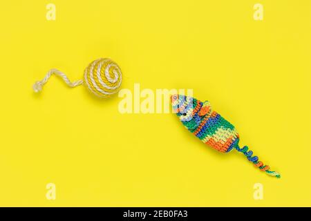 Artificial mouse and ball for playing cats on a bright yellow background. View from above. Colorful knitted pet toys Stock Photo