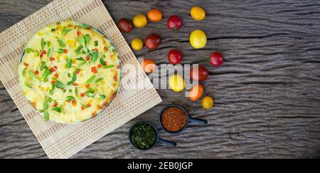 Homemade vegetable pizza with cherry tomatoes and other ingredients on a wooden background Stock Photo