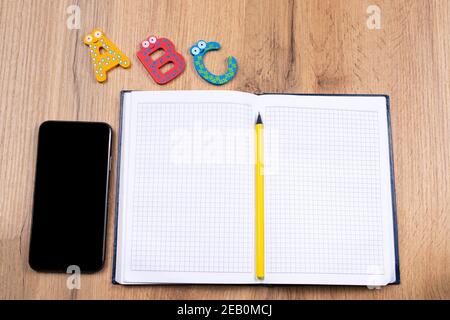 Learning foreign language lifestyle in online school concept on wooden table and empty screen black smartphone. E-learning concept Stock Photo