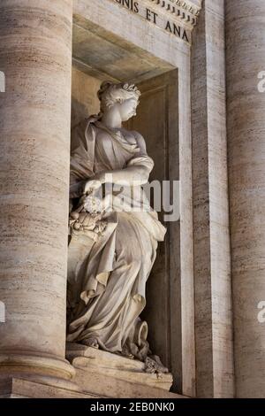 Statue of Abundance holding a horn of plenty in niche of the Trevi Fountain at night in Rome, Italy Stock Photo
