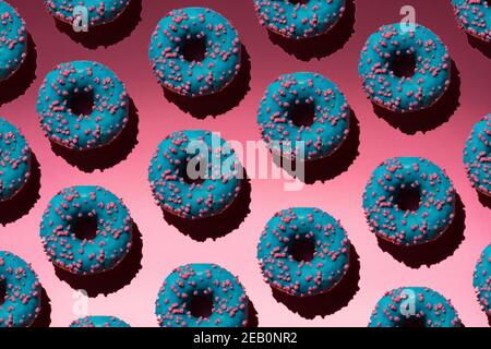 Blue donuts with pink crumb on a pink background pattern Stock Photo