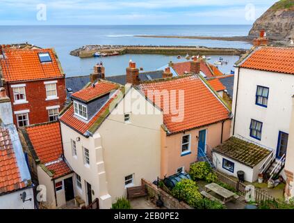 View of  harbour and traditional houses with red tiled roofs in Staithes a seaside village in North Yorkshire on the north eastern coast of England UK Stock Photo