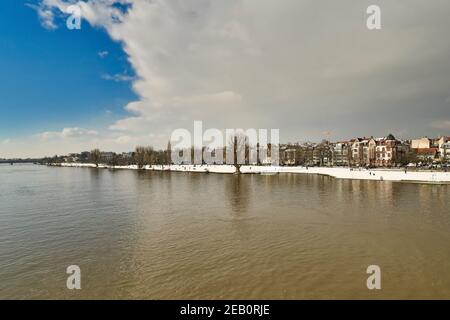 Heidelberg, Germany - February 2021: Gray clouds covering blue sky over snow covered Neckar riverbank in winter Stock Photo