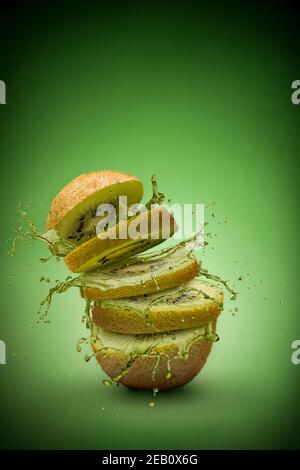sliced kiwi fruit with splashing juice on green background Stock Photo