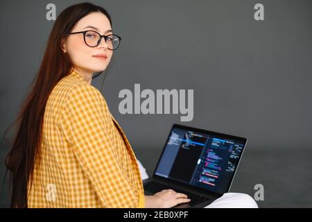 Portrait of young woman mobile developer with laptop, writes program code on a computer, programmer work. Stock Photo