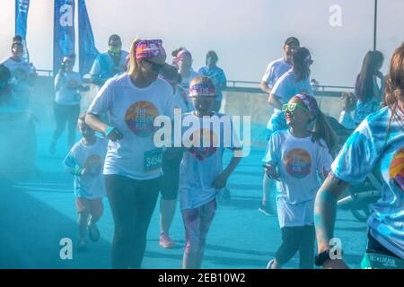 April 6 2019 Tulsa USA Mother and children run laughing through blue powder at color station at Color - holi run - looks grainy and blurred because Stock Photo