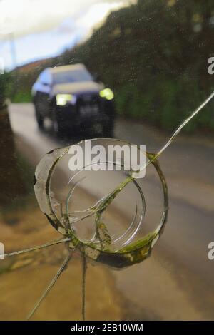 Car on the road reflected in broken mirror Stock Photo