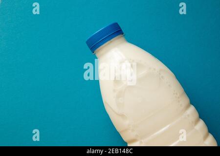 Fresh dairy product in full plastic bottle for milk, kefir or yoghurt with blue cap in center of blue background. Top view. Stock Photo