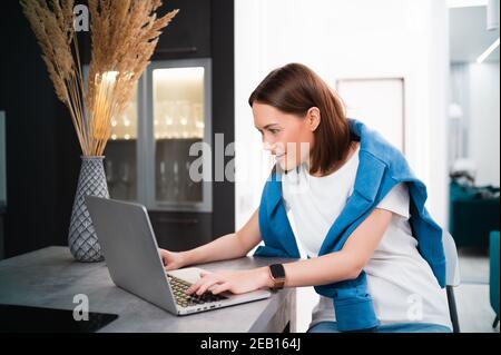 Female gamer playing video game from home using laptop. Professional player testing online video games on her personal computer with modern technology Stock Photo