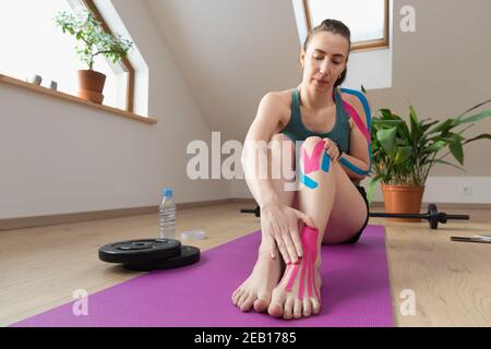 Young fit women showing kinesiology tape on her foot. Muscle treatment, rehabilitation sport and physical therapy. Stock Photo