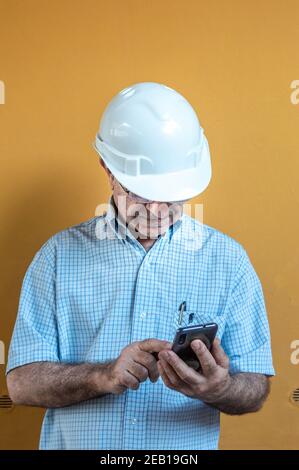 White man in a white engineer helmet holding a mobile. Stock Photo