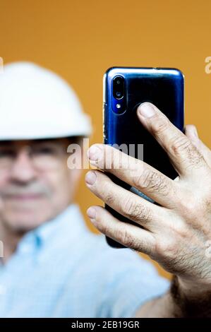White man in a white engineer helmet holding a mobile. Stock Photo