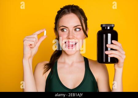 Close-up portrait of attractive cheerful hungry girl taking drugs healthy energy remedy licking lip isolated over bright yellow color background Stock Photo