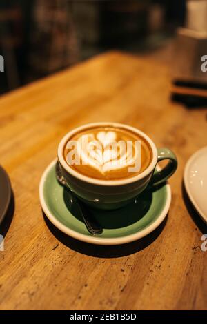 coffee latte art in green ceramic cup on wood background Stock Photo