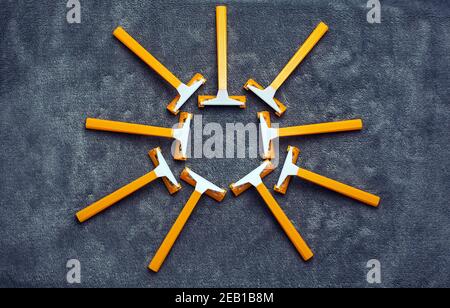 Many orange yellow shaving razors in sun shape on gray background Stock Photo