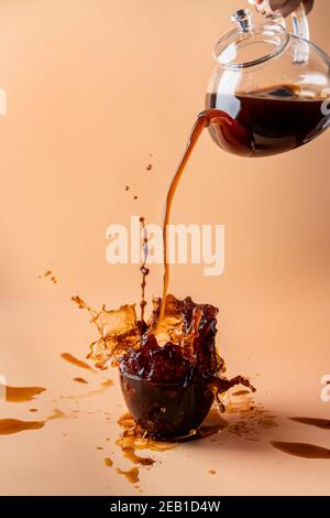 pouring coffee in a cup creating splashes with ingredients on colorful orange and pink background Stock Photo