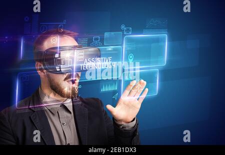 Businessman looking through Virtual Reality glasses with ASSISTIVE TECHNOLOGY inscription, new technology concept Stock Photo