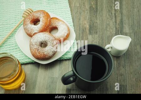 Donuts sprinkled with powdered sugar on a plate. Powdered sugar donuts with copy space Stock Photo