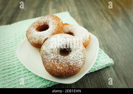 Donuts sprinkled with powdered sugar on a plate. Powdered sugar donuts with copy space Stock Photo
