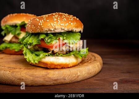 Burger with chicken cutlet, cheese, tomatoes and herbs. Stock Photo