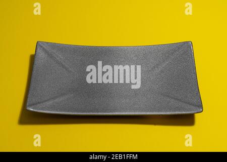 empty dark plate on yellow background Stock Photo
