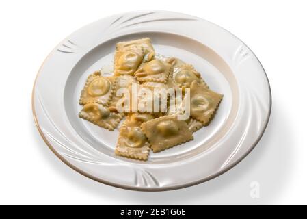 Ravioli - Italian stuffed egg pasta topped with pine nuts and butter sauce in white dish on white background Stock Photo