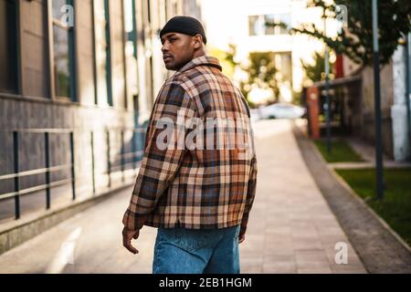 Confident stylish young afro american man walking on a street, back view Stock Photo