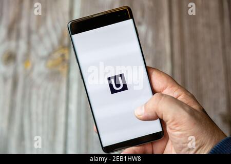 A mobile phone or cell phone being held by a hand with the Uswitch app open on screen Stock Photo