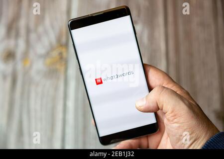 A mobile phone or cell phone being held by a hand with the What3words app open on screen Stock Photo
