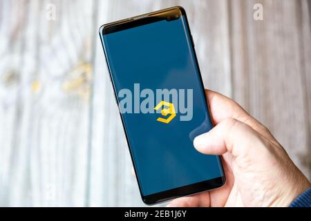 A mobile phone or cell phone being held by a hand with the Coinbase Crypto app open on screen Stock Photo